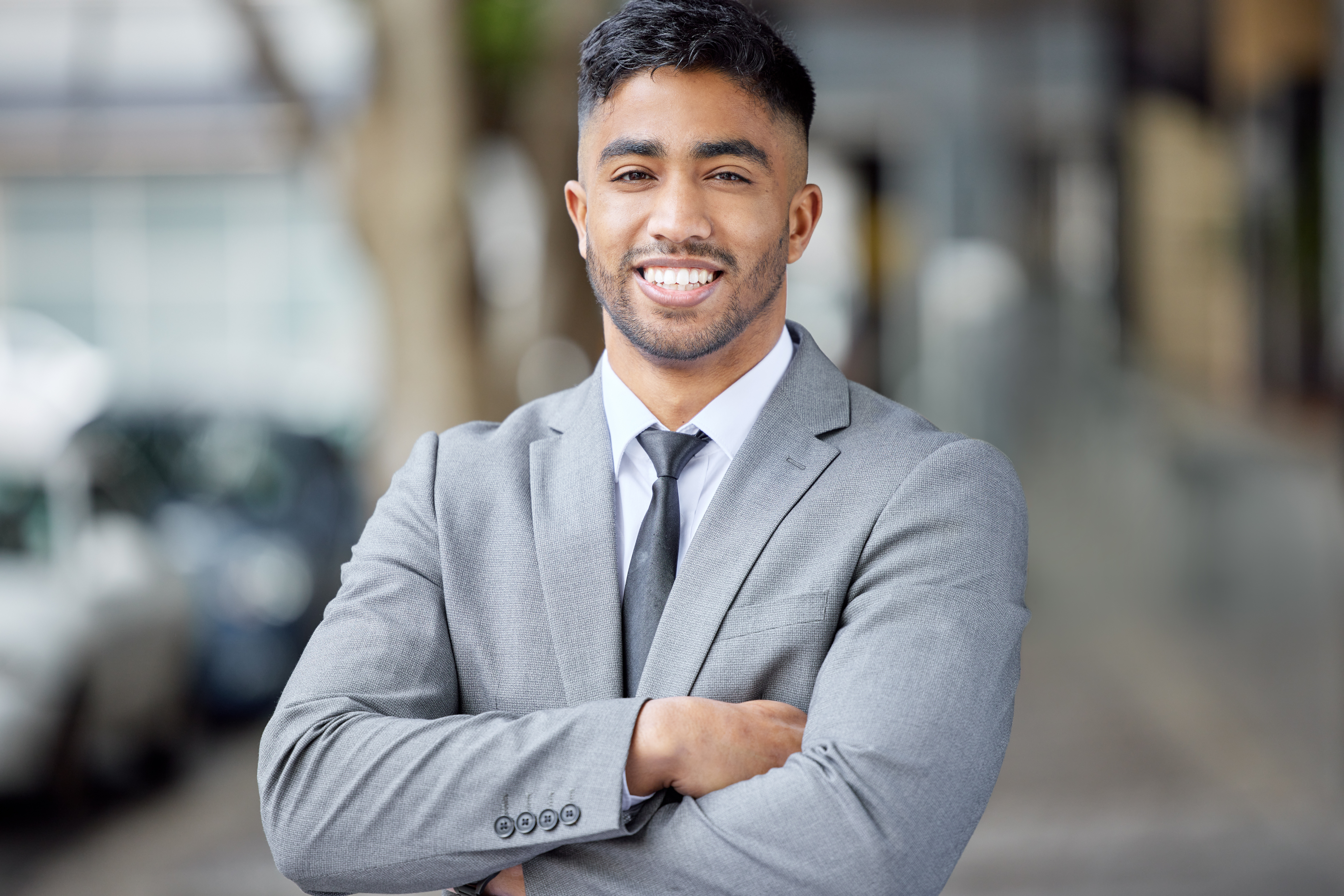 A young sales professional smiling with arms crossed, demonstrating confidence.