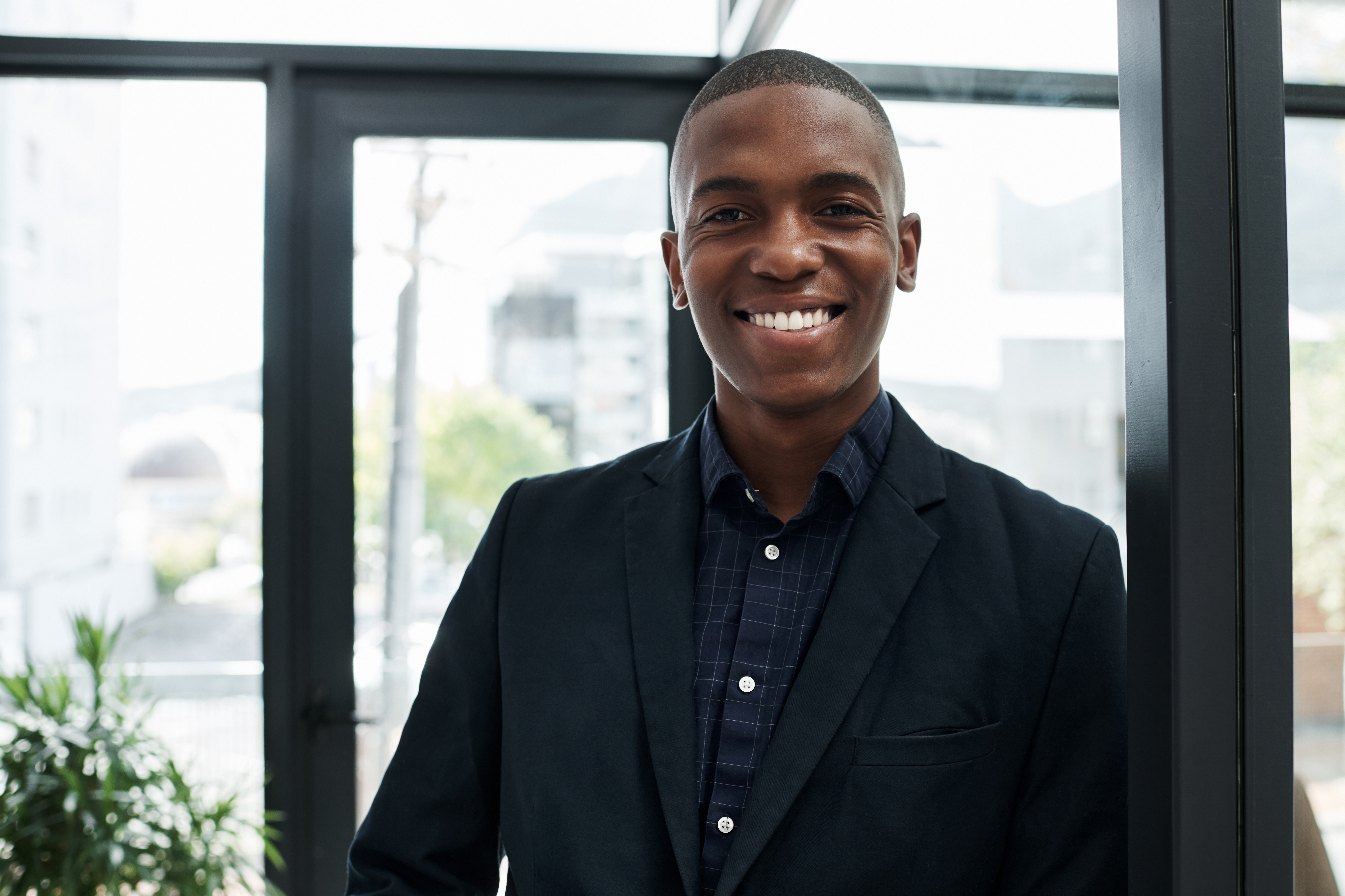 A young business professional in an office setting smiling confidently.