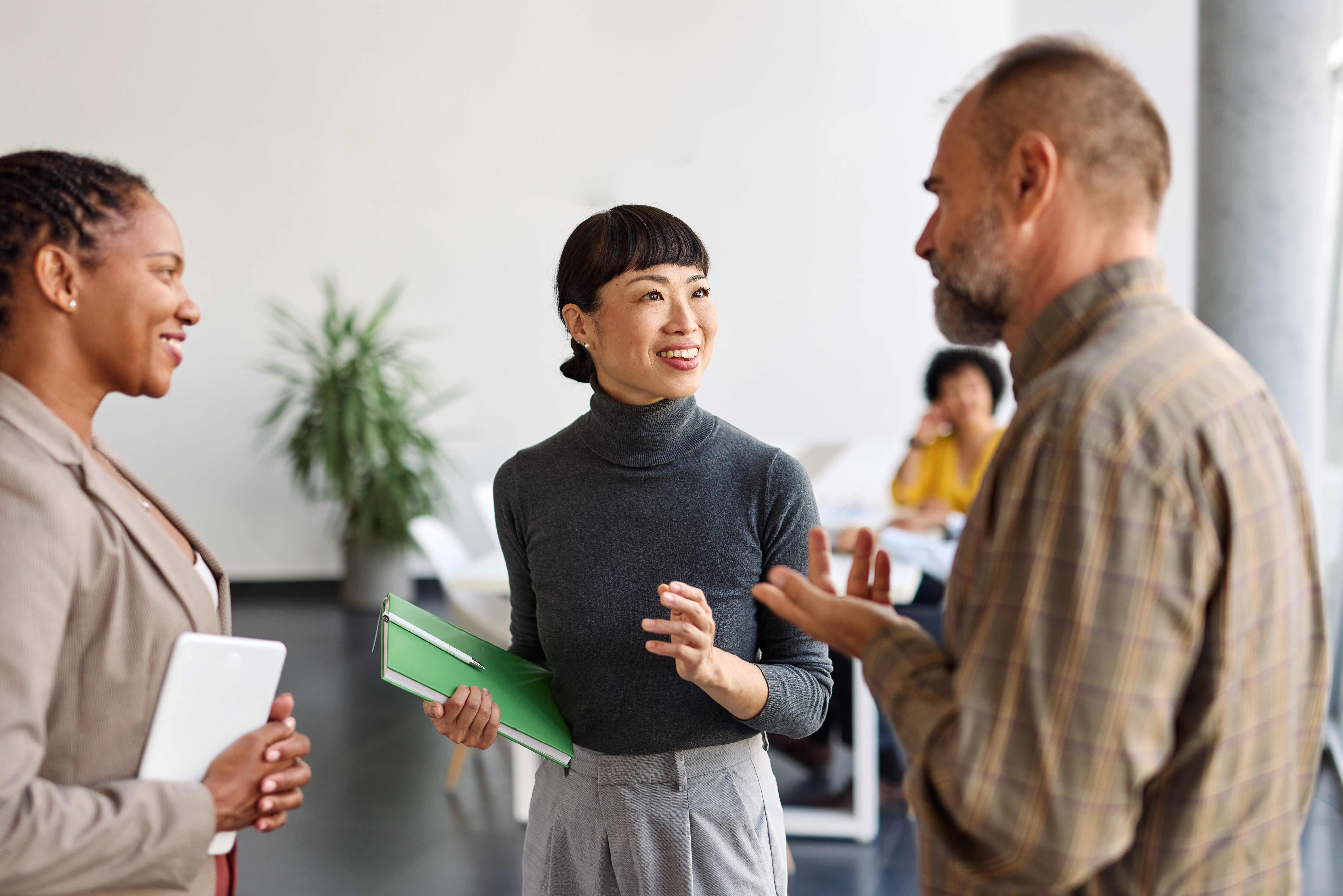 Business professionals engaged in a discussion while standing in a modern office setting